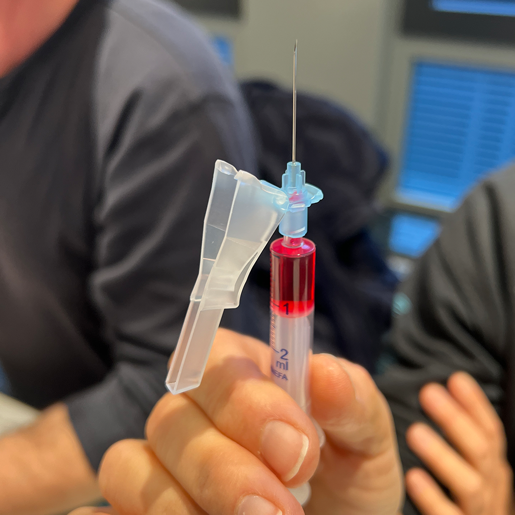 Teilnehmer hält im Medizintraining eine aufgezogene Spritze zur Übung in der Hand.