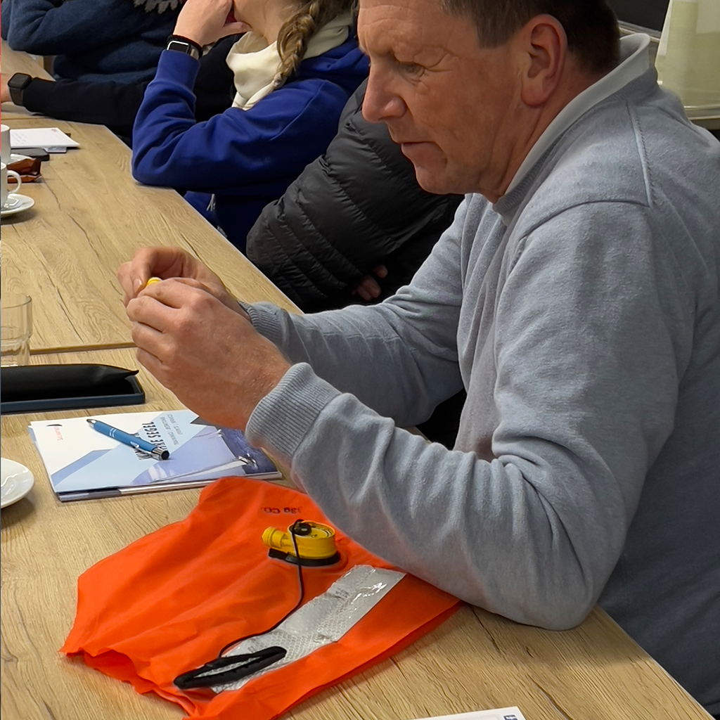 Teilnehmer studiert im Unterricht den hydrostatischen Auslöser einer Rettungsweste, wie er z. B. bei Spinlock-Westen genutzt wird