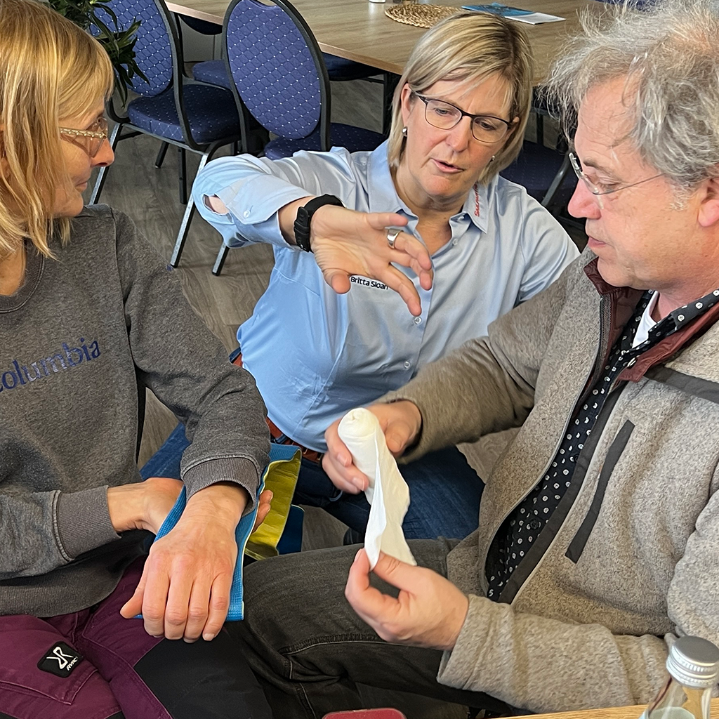 Britta unterstützt Teilnehmer beim Anlegen einer Splint-Spiegel-Schiene im Offshore-Sicherheitstraining