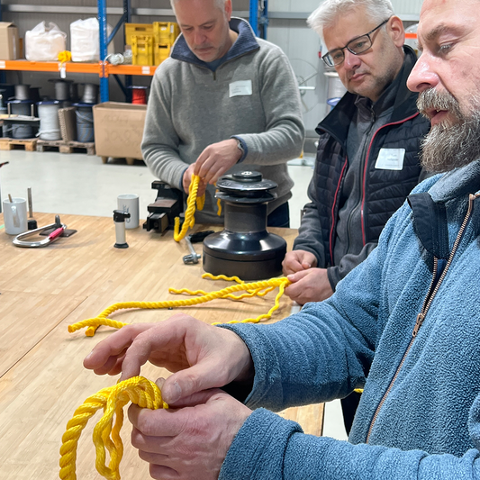 Trainer erklärt Teilnehmern an dreikardeeligem Tauwerk die Technik des Spleissens im Kurs.