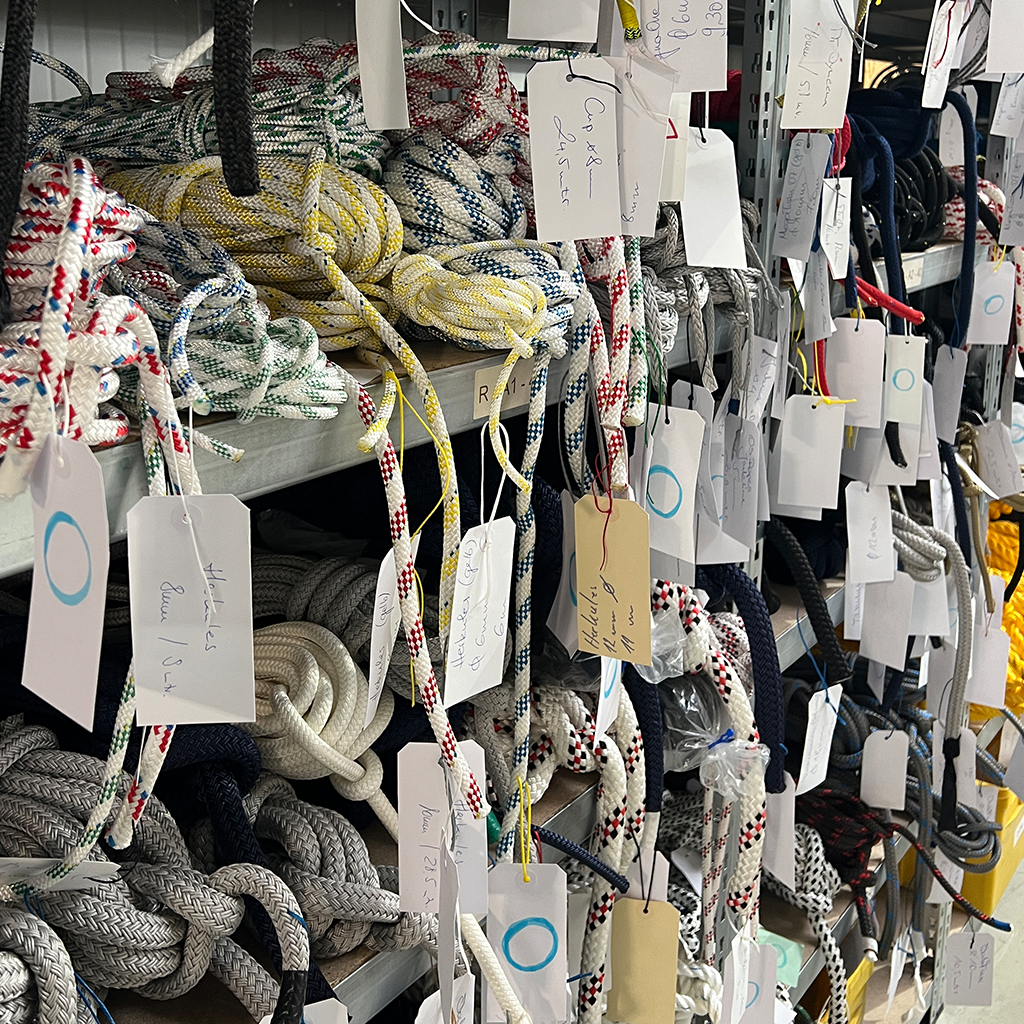 Lagerregal mit unterschiedlichen Leinen und Tauwerk, beschriftet zur Veranschaulichung der Materialkunde.