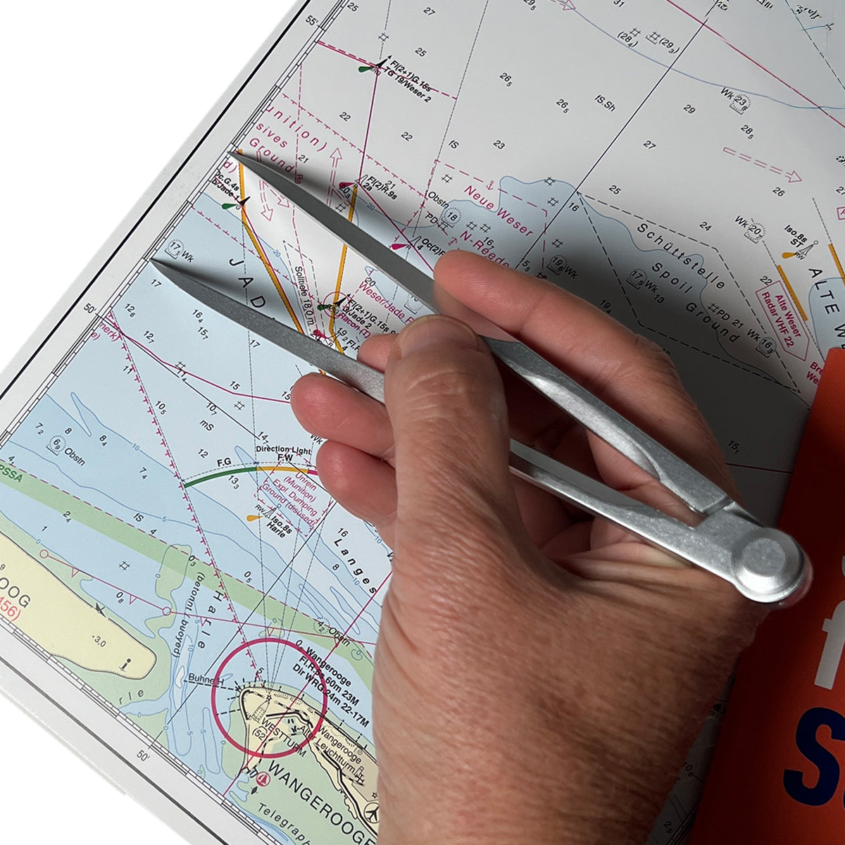 Kartenzirkel in der Hand beim Abgreifen von Distanzen auf der Seekarte, präzise Navigation.