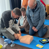 Trainer demonstrieren im Medizin-auf-See-Training den Einsatz von Beatmungsbeutel und Defibrillator.