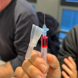 Teilnehmer hält im Medizintraining eine aufgezogene Spritze zur Übung in der Hand.