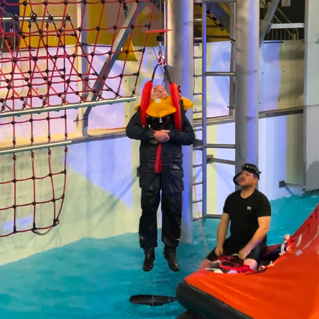 Teilnehmer wird im Offshore-Trainingsbecken mit Helikopteranlage aus Rettungsinsel geborgen – Offshore-Sicherheitstraining