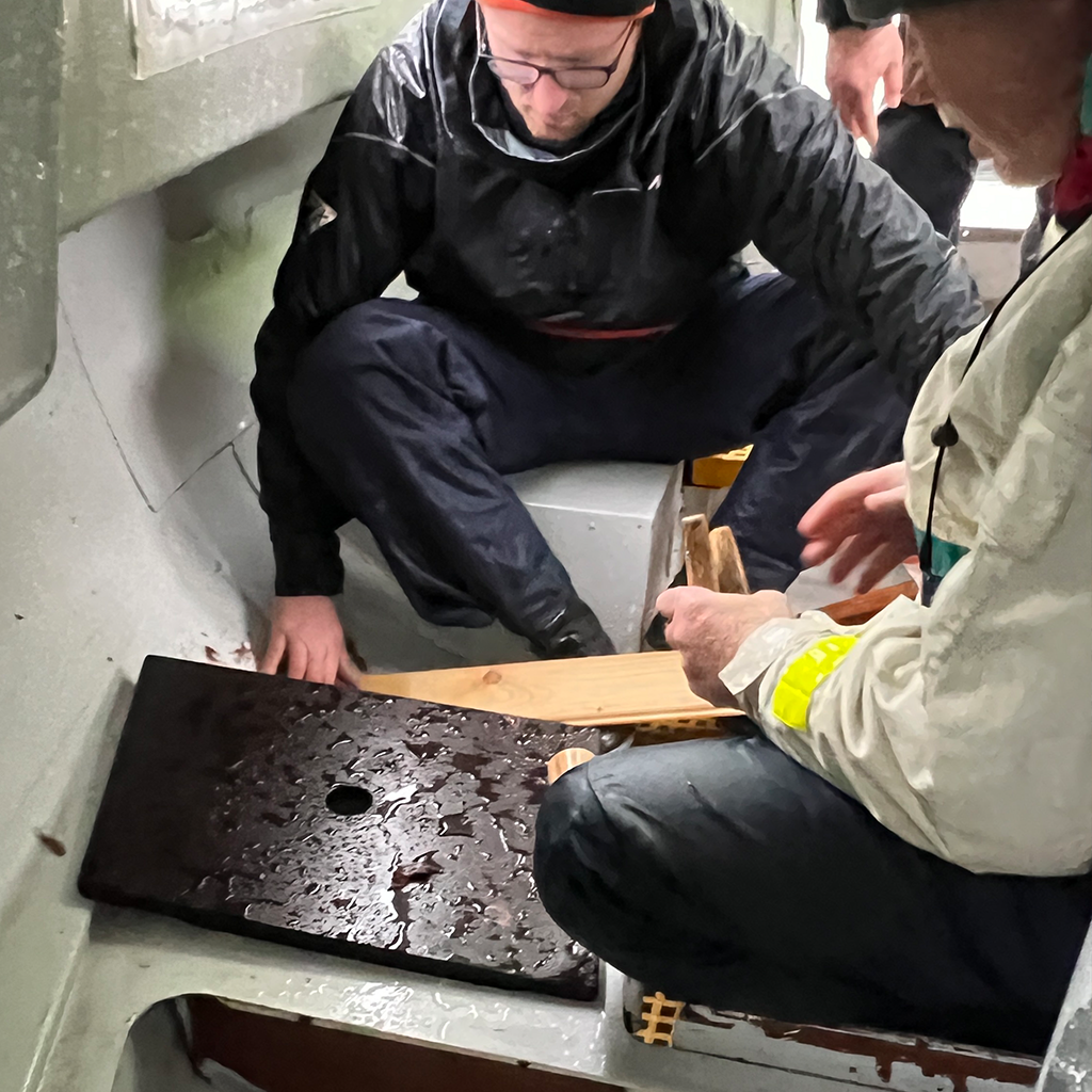 Zwei Teilnehmer üben im Leckageboot den Umgang mit Wassereinbruch beim Offshore-Sicherheitstraining