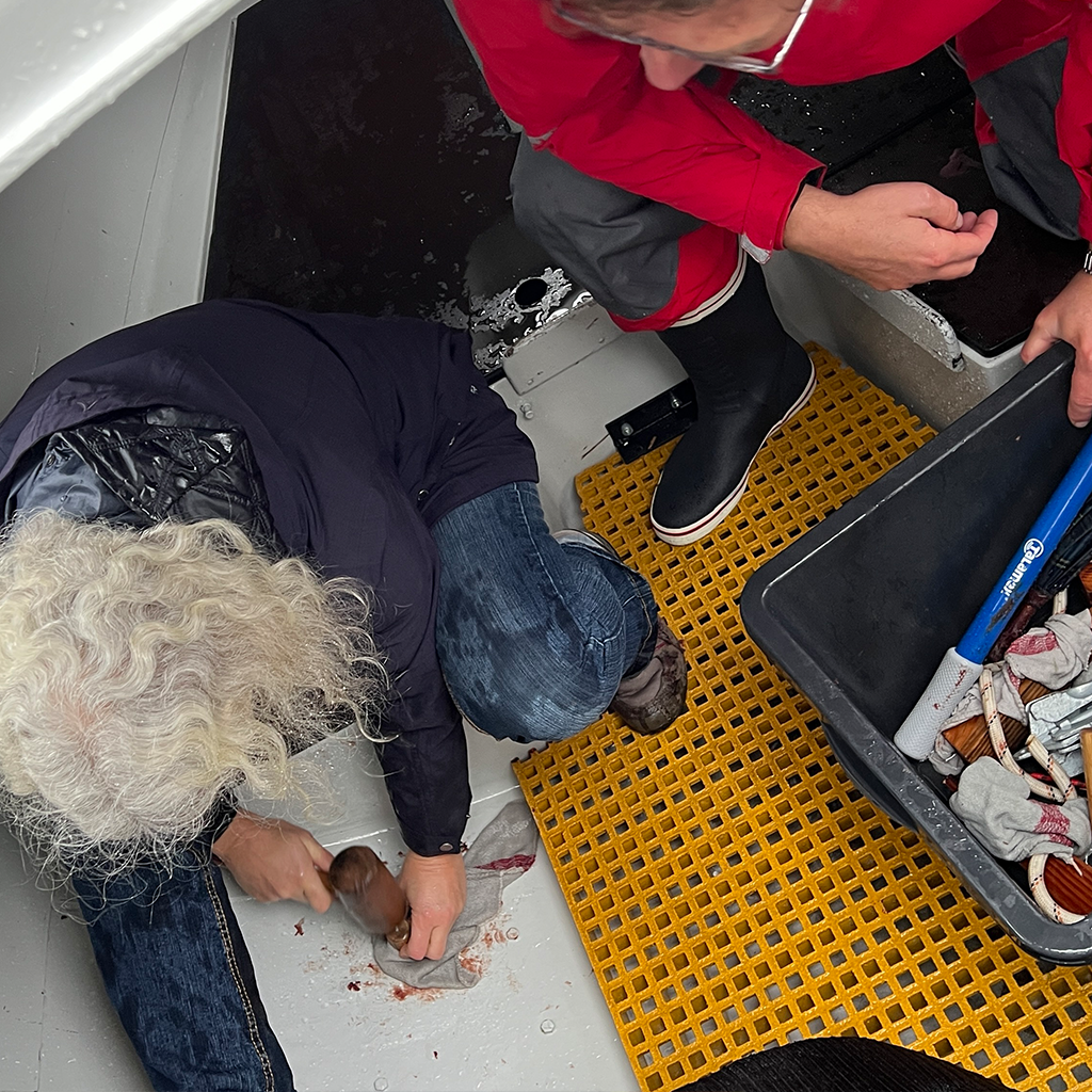 Teilnehmer im Leckageboot üben Leckbekämpfung und testen Materialien, um Wassereinbruch unter Kontrolle zu bringen beim Offshore-Sicherheitstraining