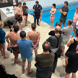 Aufnahme von oben: Teilnehmer verfolgen Trainer Michael bei der Demonstration zur Auslösung einer Rettungsinsel im Offshore-Sicherheitstraining