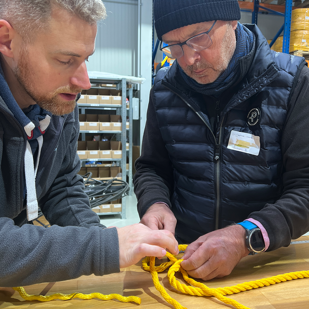 Trainer erklärt einem Teilnehmer die Detailarbeit am Tauwerk beim Anfertigen eines Spleiss.